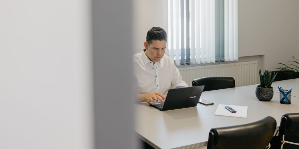 Stefan Schuler arbeitet in einem Besprechungsraum an seinem Laptop.