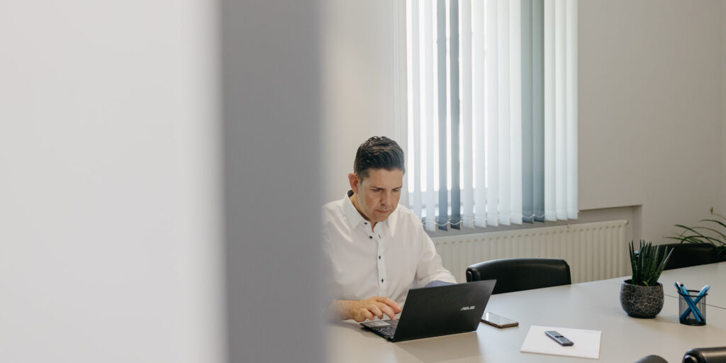 Stefan Schuler arbeitet in einem Besprechungsraum an seinem Laptop.