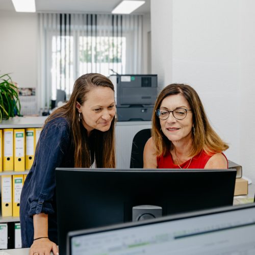 Zwei Mitarbeiterinnen der Steuerkanzlei Schicker & Kollegen besprechen am Monitor einen Vorgang